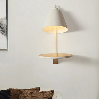 Modern white gray tapered wall sconce with conical shade and wooden shelf providing warm bedroom ambient lighting
