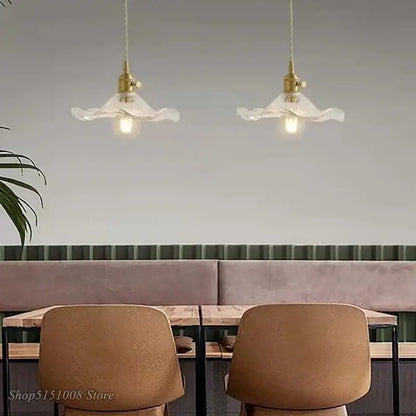 Two elegant brass-finished pendant lights with colorful glass shades hang above a dining area cord pendant installation