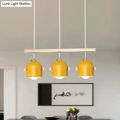 Modern yellow dome island light with three metal dome shades suspended from a wooden bar by decorbites