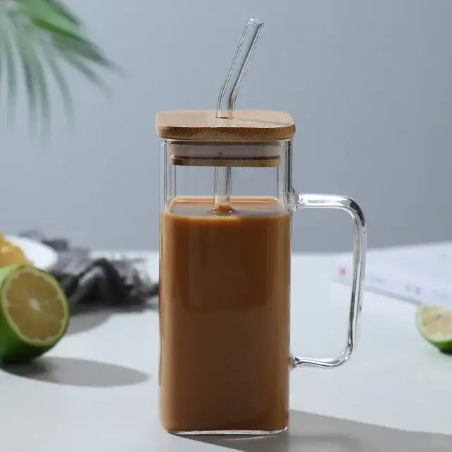 Modern green handle square glass mug made of clear glass with bamboo lid and handle filled with brown iced coffee