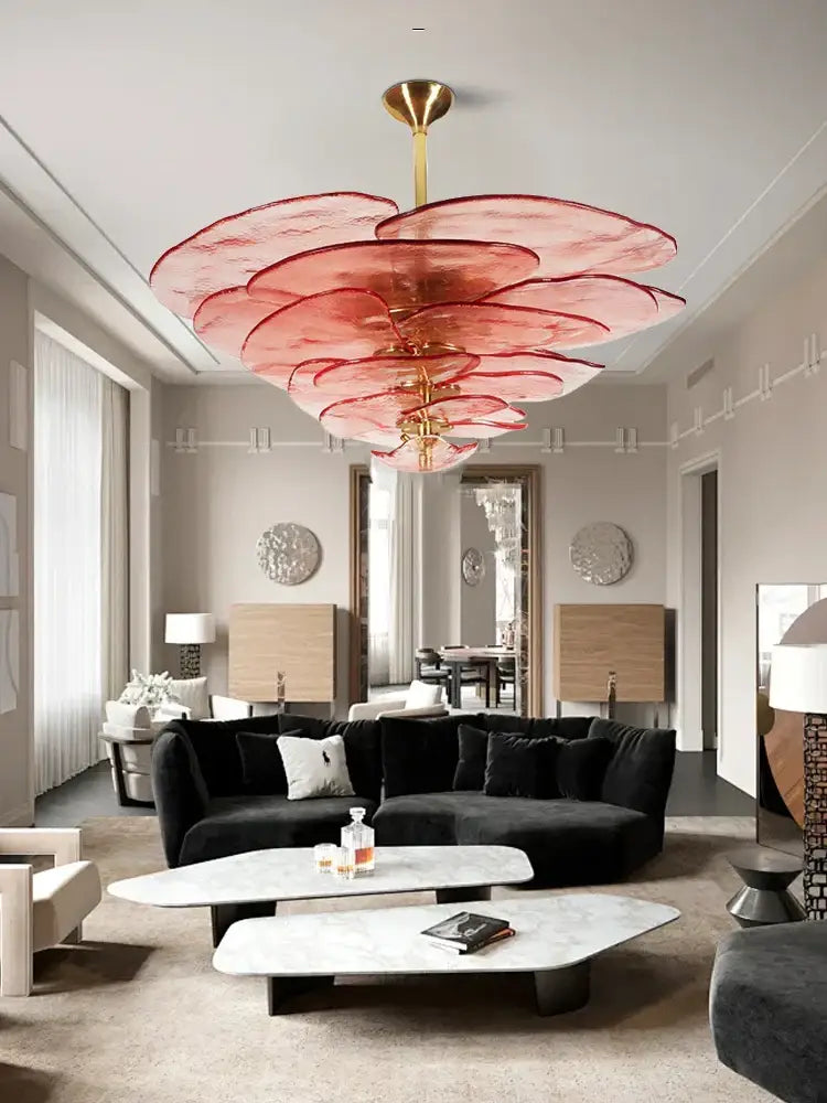 A striking pink layered glass chandelier with a gold-toned fixture complements modern green leaf glass ceiling decor