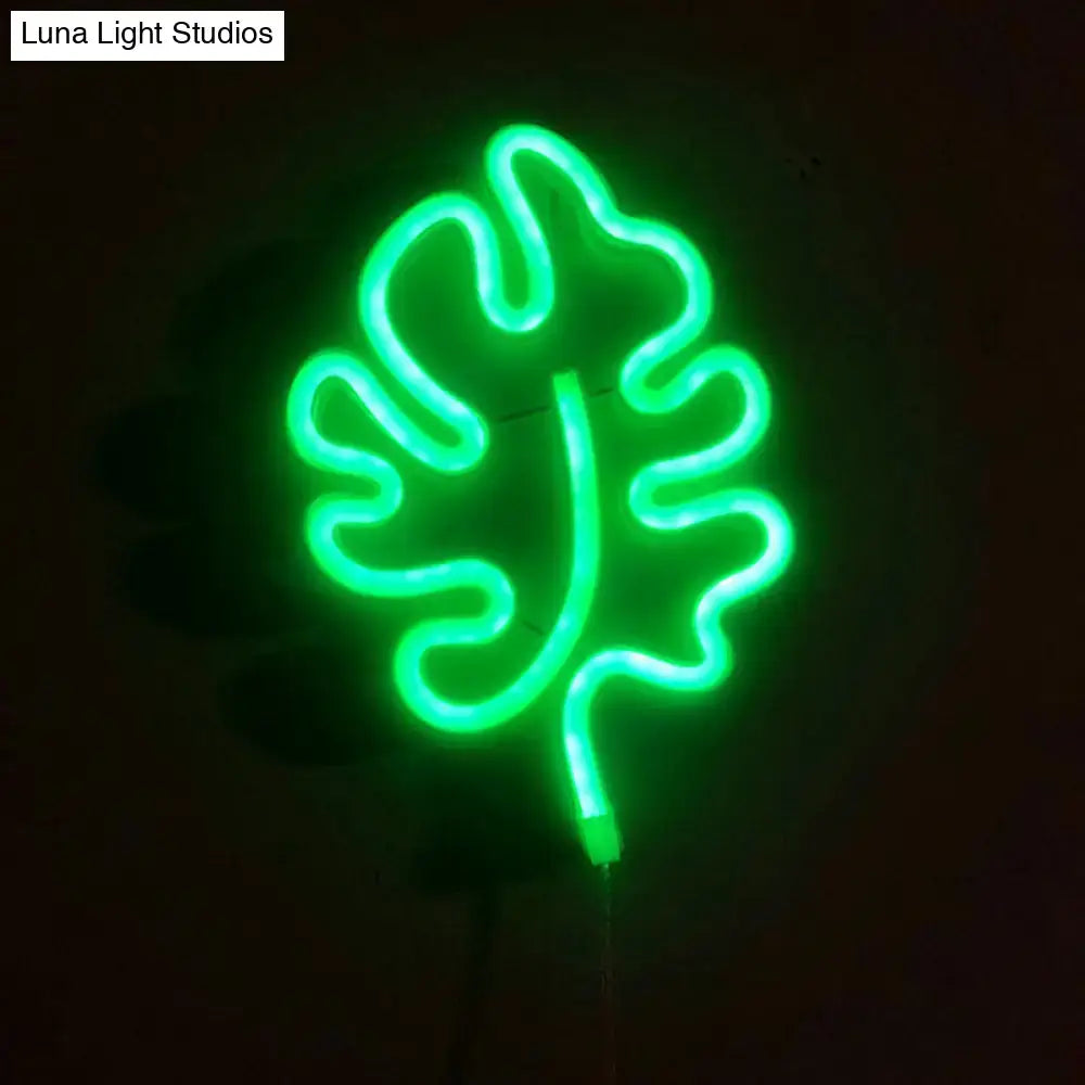 A modern itty bitty green leaf neon sign bedroom wall light with remote control glowing brightly