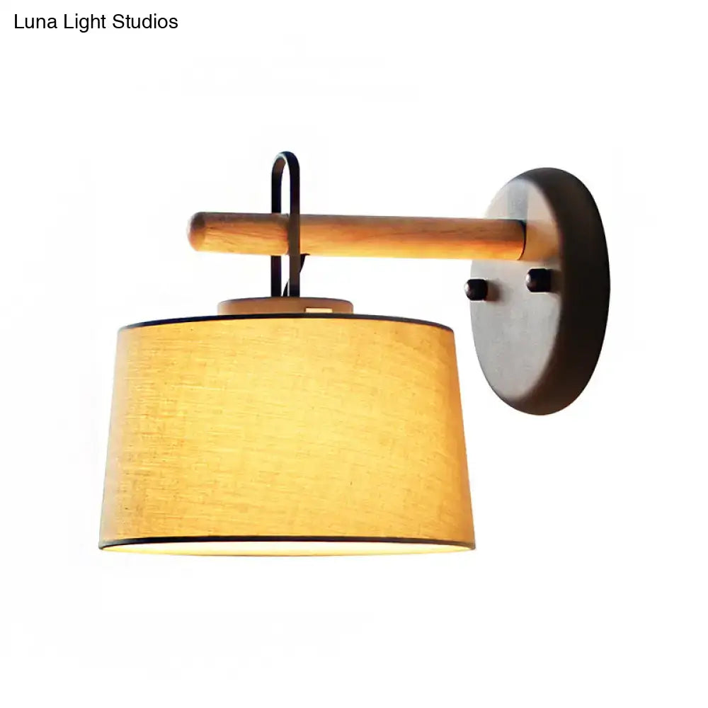 Modern grey drum shade wall lamp with warm-toned textured fabric lighting fixture mounted on wooden arm for bedroom use