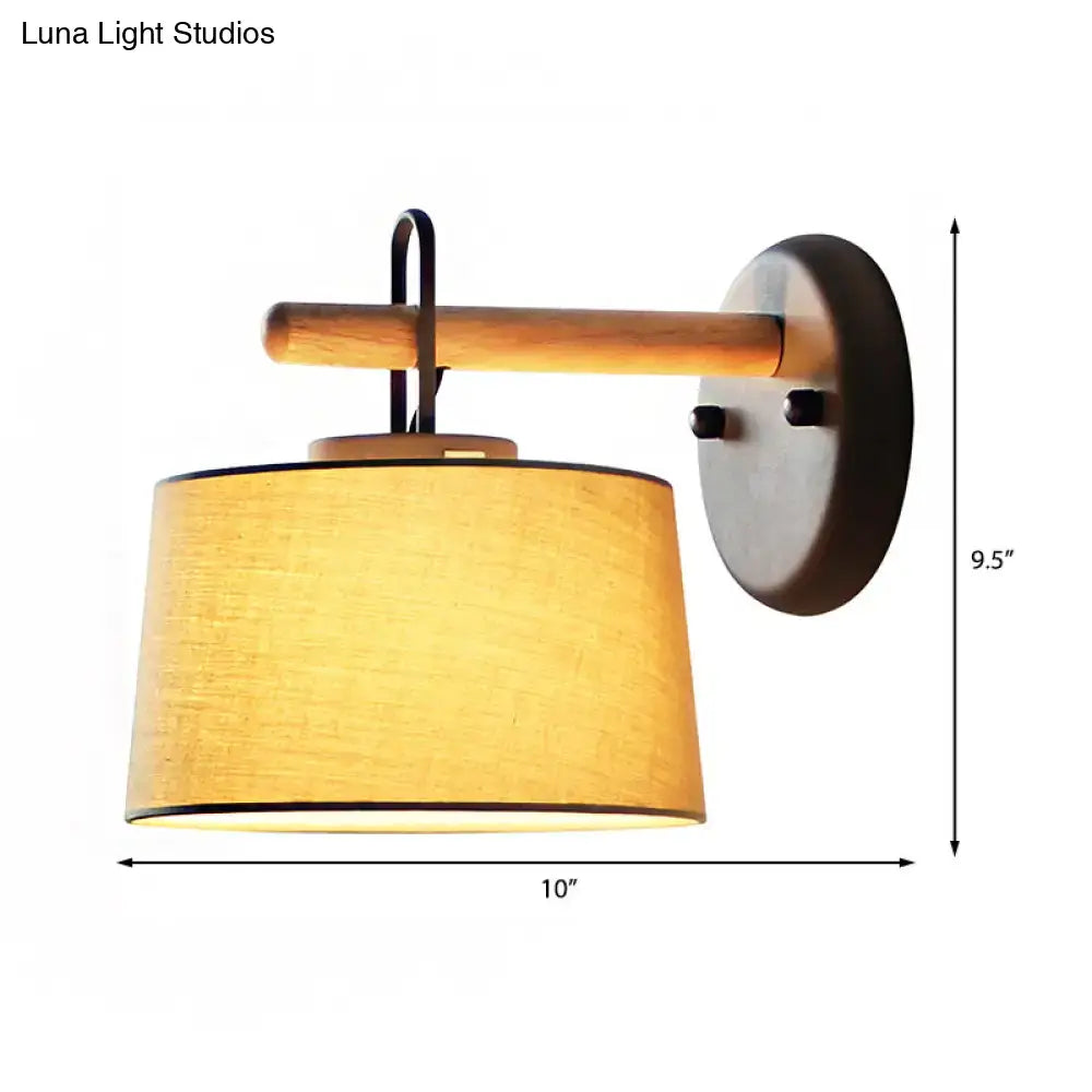 Modern grey drum shade wall lamp with warm-toned fabric lighting fixture mounted on wood arm for bedroom lighting