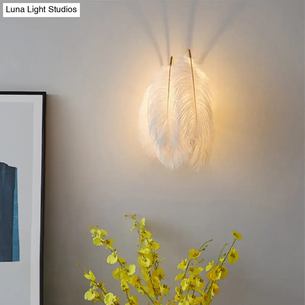 Modern grey and white furry goose feather wall lamp with soft white feathers and slender gold-toned mounting rods for bedroom