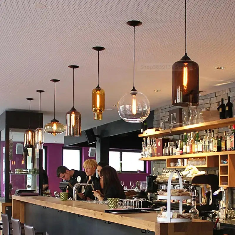 Modern hand blown colorful stained glass pendant lights with warm amber and clear glass and black metal fixtures for kitchen decor