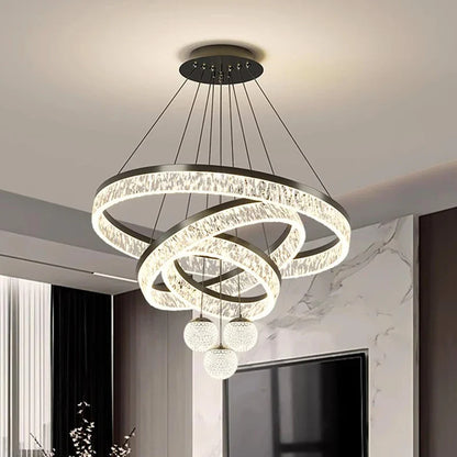 Modern black metal chandelier with interlocking crystal rings and three spherical LED pendant lights for indoor living spaces