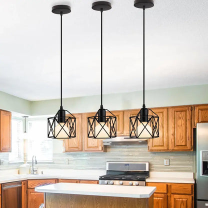 Three black modern industrial cage pendant lights with a geometric metal design hang above the kitchen island for decorbites