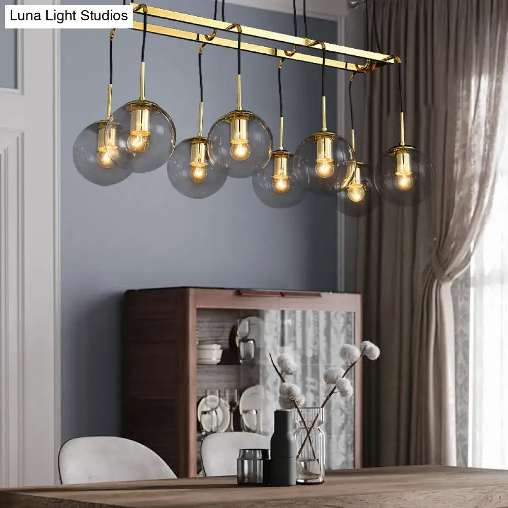 Gold-toned modern chandelier with five smoke glass globes on brass frame for industrial island lighting by DecorBites™