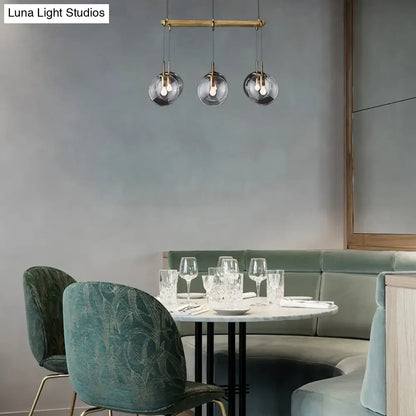 Modern three-light pendant fixture with brass hardware and frosted globes for island lighting with smoke glass accents