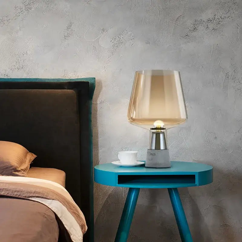 A modern industrial table lamp with a translucent amber smoked glass shade and decorbites leimu cement base