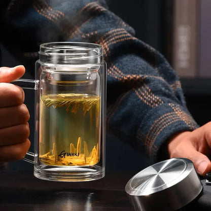Modern insulated clear glass tea cup with handle lid and transparent chamber holding yellow tea leaves