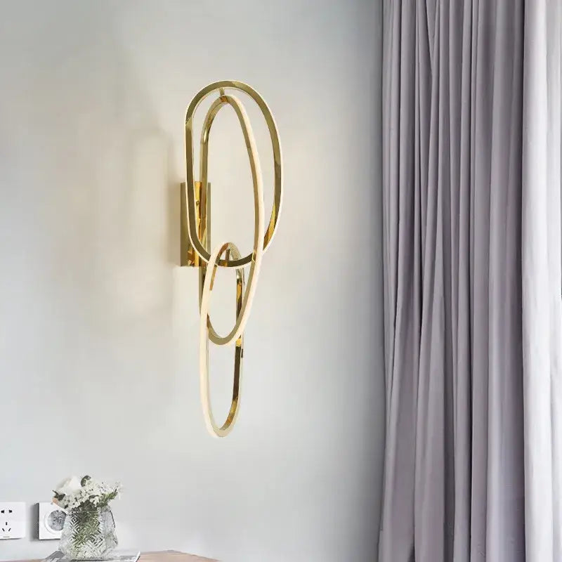 Modern interlocking oval gold wall sconce lighting fixture featuring gold-toned rings for bedroom decorbites gold led lighting