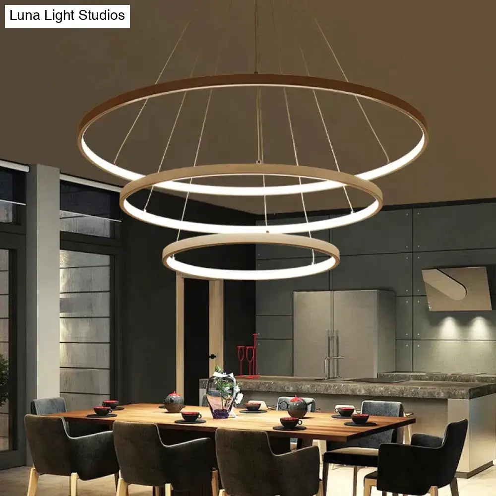 Modern pendant lights featuring three-tiered interlocking rings with matte wood finish and warm white led lighting for dining room
