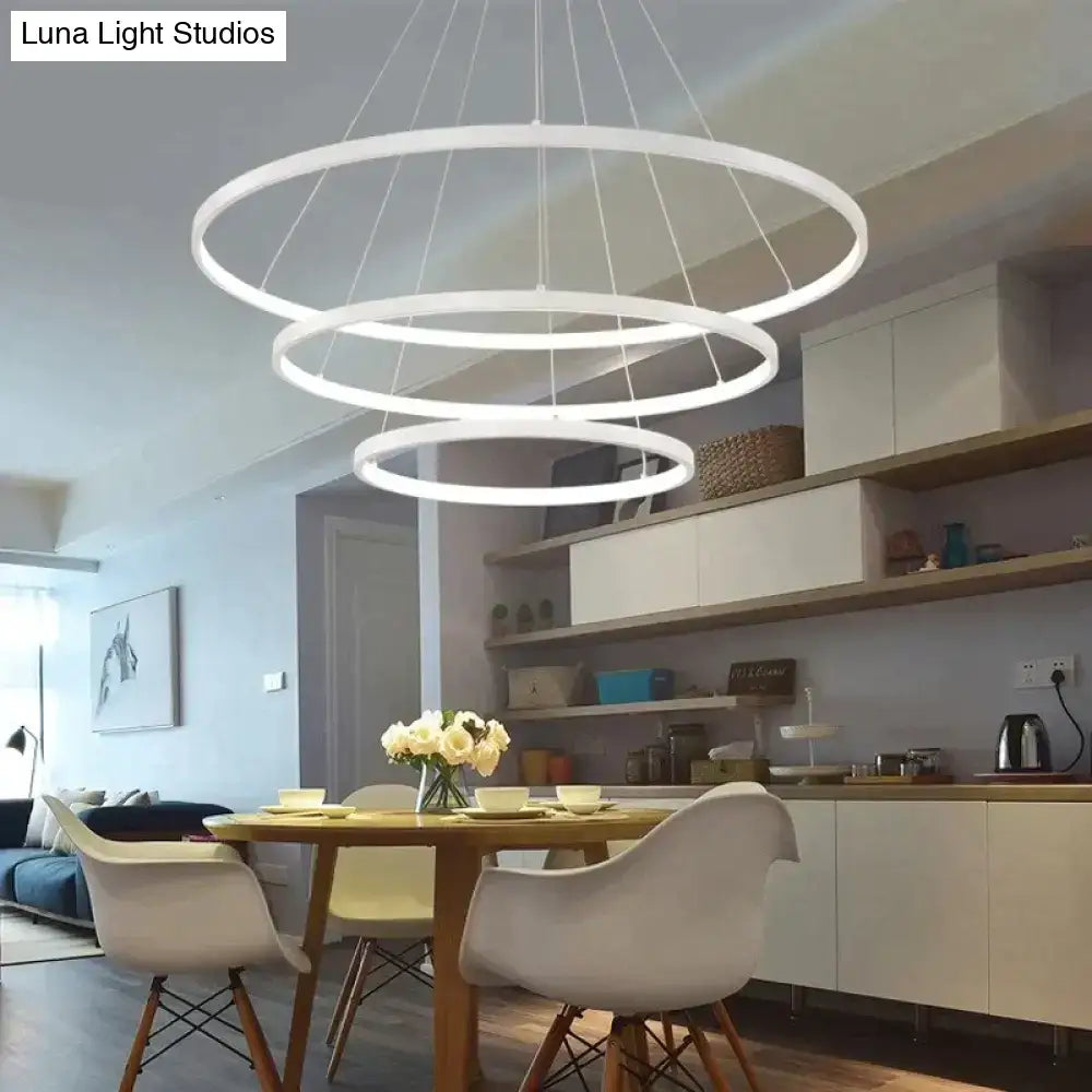 Modern pendant lights featuring white circular interlocking led rings suspended by thin cords for dining room use