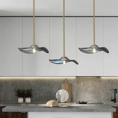 Three elegant wave-shaped glass plated pendant lamps with translucent blue and silver shades for kitchen lighting