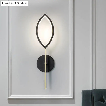 Modern leaf wall light with sleek black frame gold finish stem and illuminated oval panel for living room use