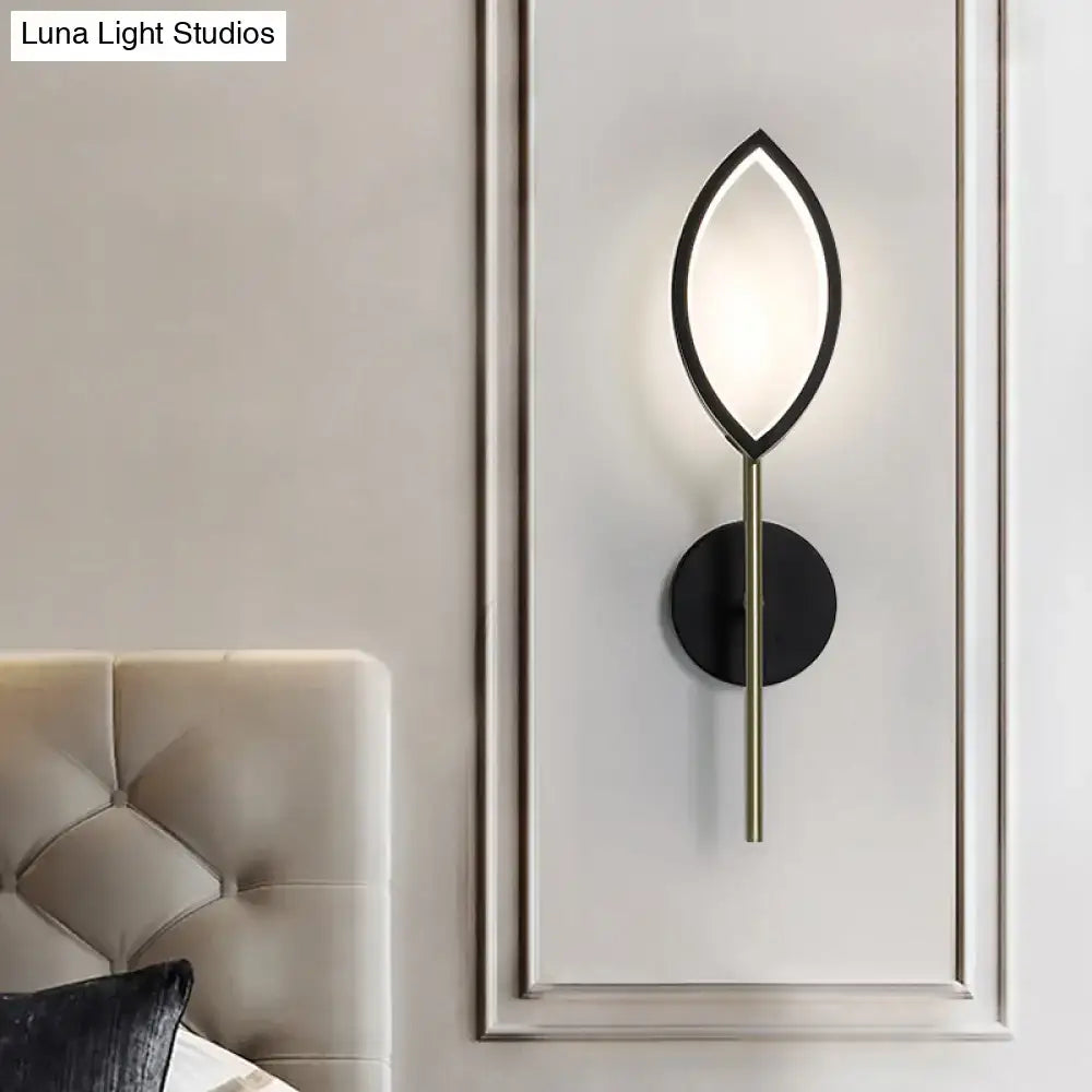 Modern leaf-shaped wall light with black metal frame, gold finish accents, and frosted glass diffuser for living room use
