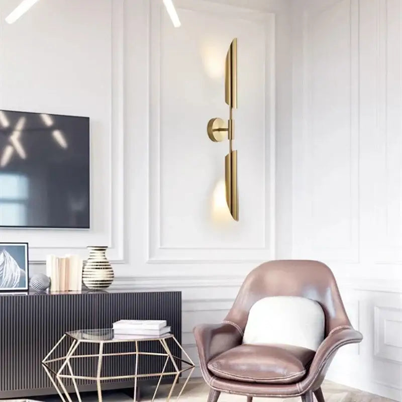 Gold-toned modern wall lamp with sleek vertical blade design and two illuminated glass bulbs for bedroom decorbites gold led