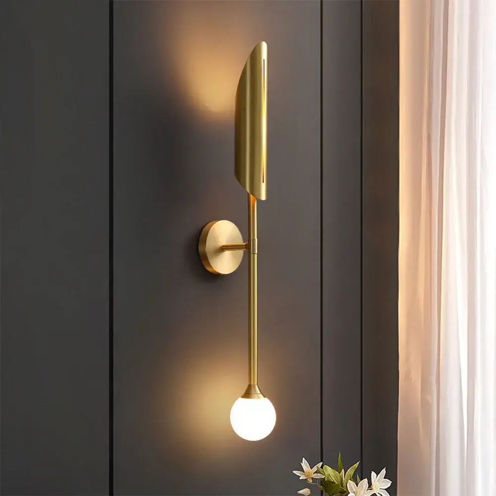 Modern leaf gold led wall lamp featuring a gold-toned elongated leaf shade and a spherical glass bulb by decorbites