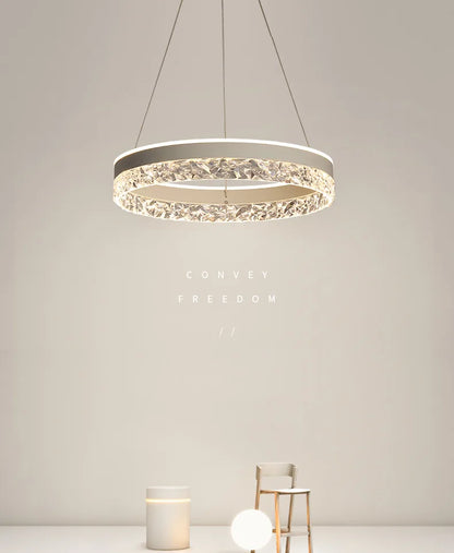 Modern led chandelier with silver frame and faceted crystal ring emitting warm light for living and dining rooms
