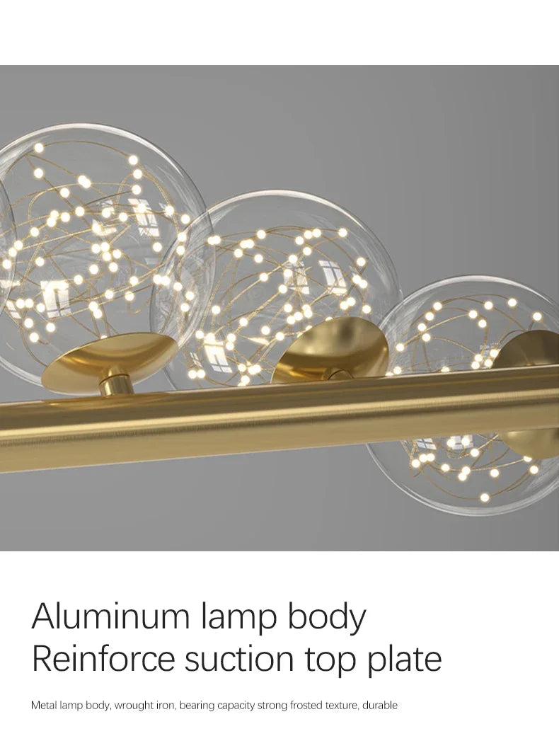Modern led long ceiling chandelier with brass finish and three clear glass spheres containing delicate string lights
