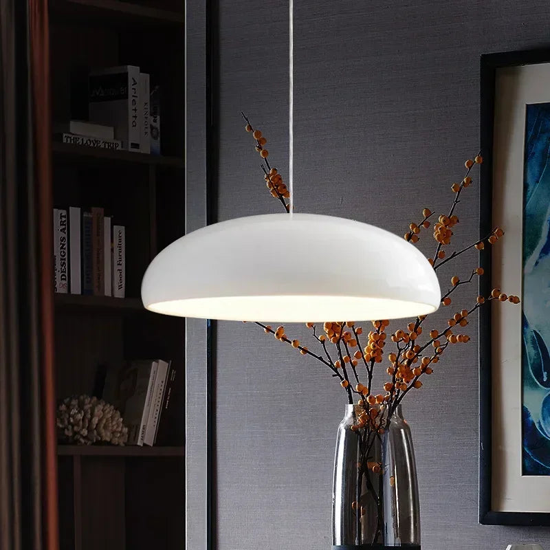A sleek modern white pendant light with a round aluminum lampshade ideal for dining table lighting