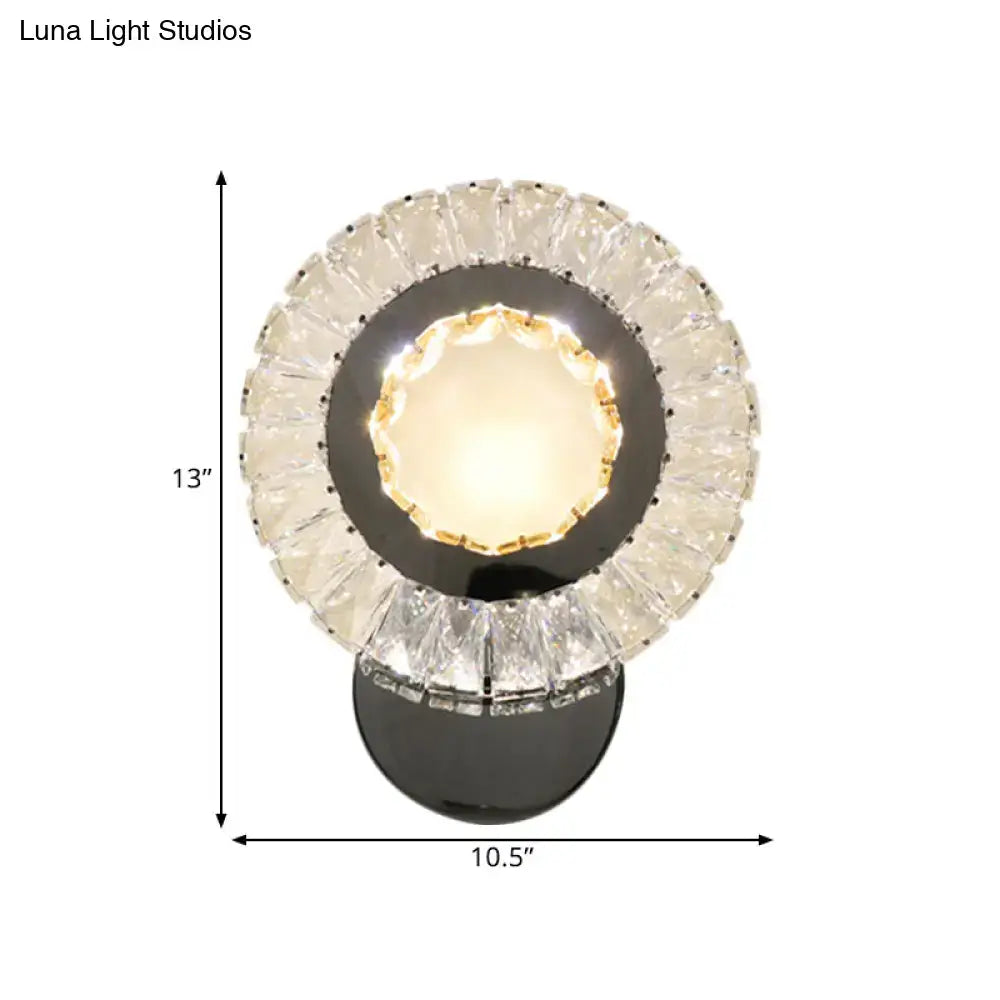 Modern led wall mount lamp with clear rectangle cut crystals and black circular base featuring warm glowing faceted crystals