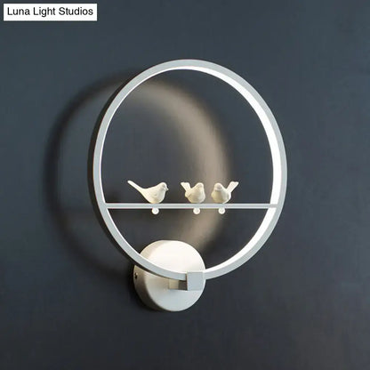 Modern led white wall lamp with sleek circular frame and three ceramic birds on integrated horizontal bar for bedroom