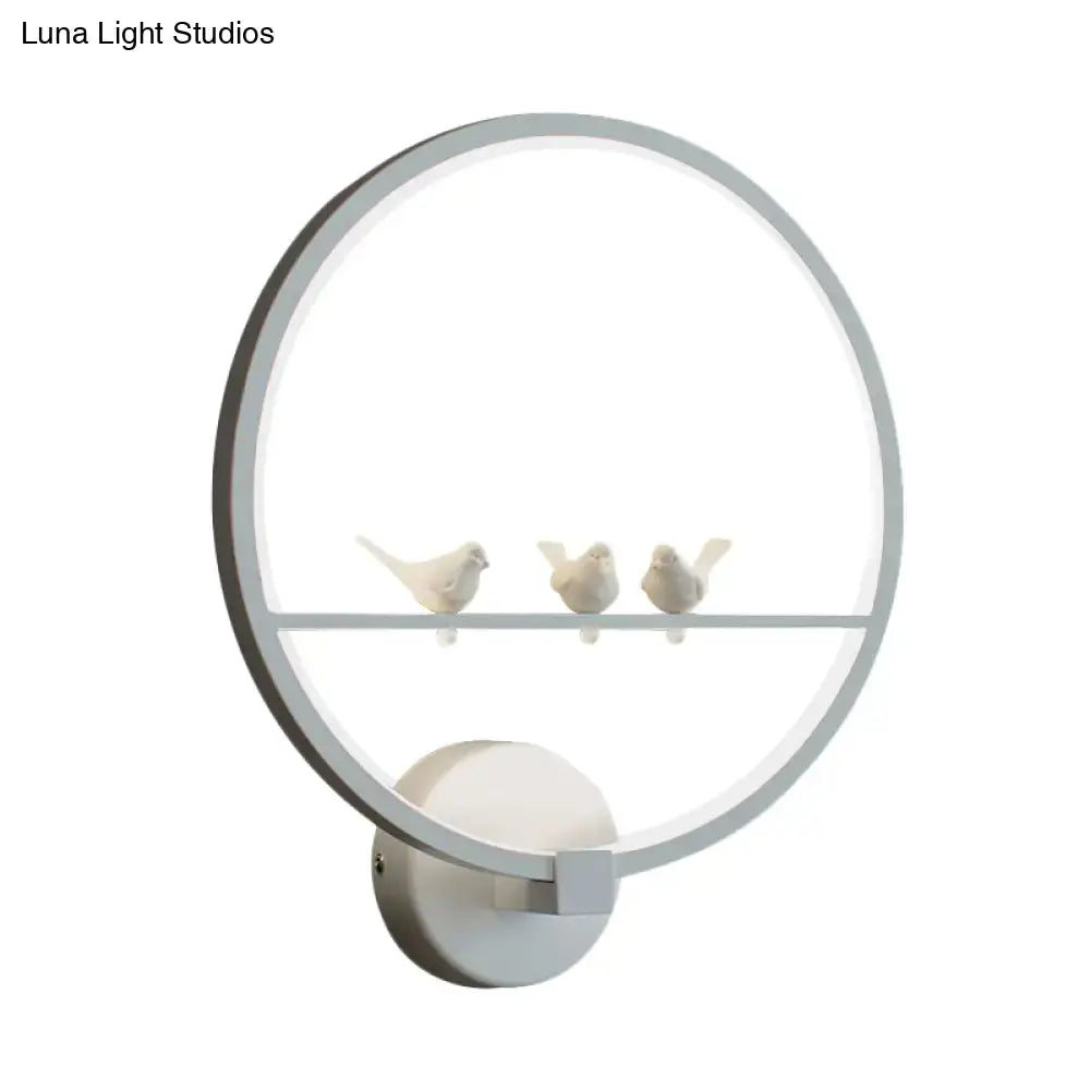 Modern led wall lamp with a sleek silver frame and three white ceramic birds on a central glass shelf for bedroom use