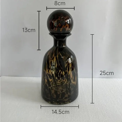 A glossy dark glass decanter with swirling amber and black leopard texture perfect for black and white dining room decorbites