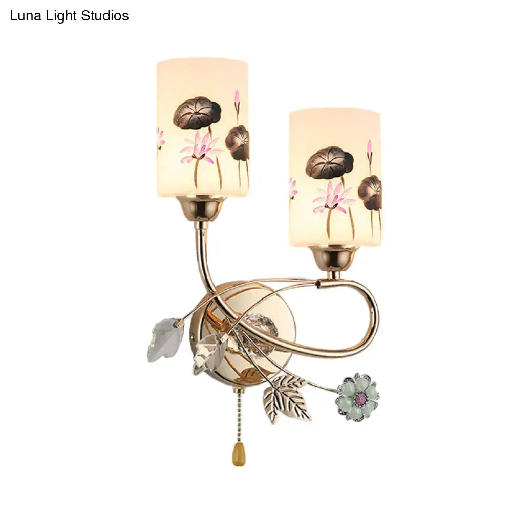 Modern lotus gold finish wall sconce with two glass shades featuring lotus designs and a decorative pull chain