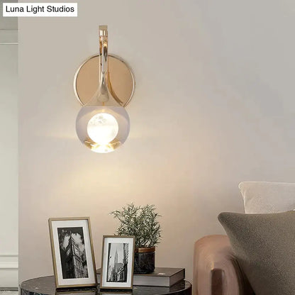 Gold-toned modern luxurious crystal led wall sconce with curved design and teardrop glass shade for bedroom lighting