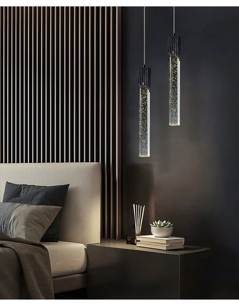 Two sleek cylindrical modern luxury crystal pendant lamps with black tops and sparkling glass bodies for home decor
