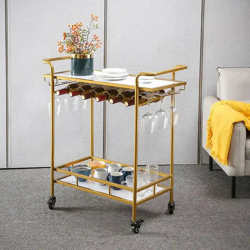Modern marble and gold drinks trolley with white marble top, gold metal frame, glass shelves, and hanging glassware racks for decorbites drinks trolley