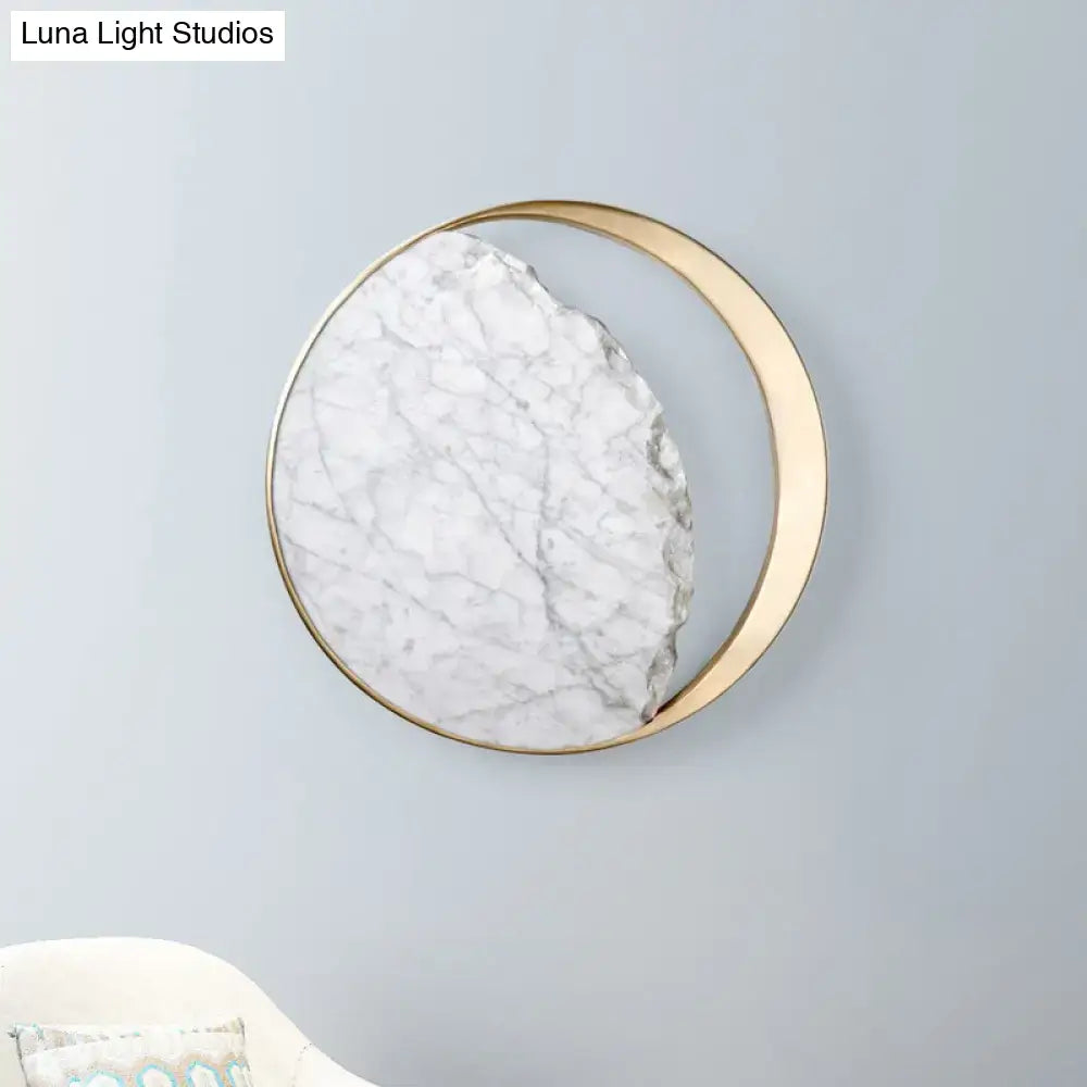 A circular wall light featuring a white marble gold led slab with gray veining in a sleek gold led wall frame