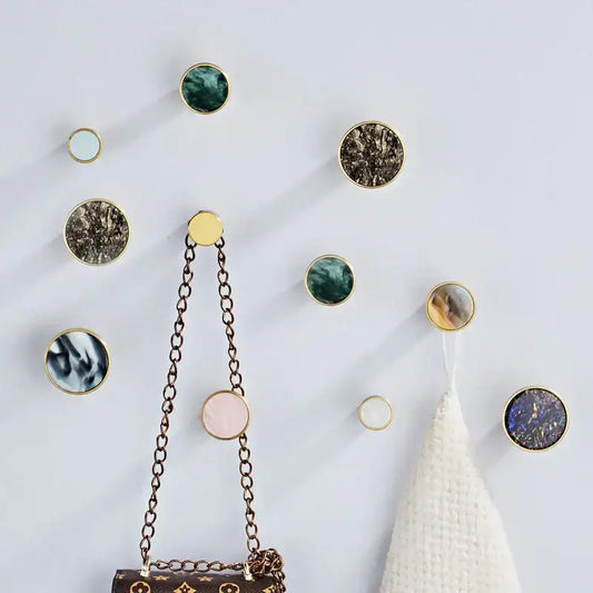 Gold-rimmed circular towel hooks with marbled stone centers in green brown pink blue and white decorbites brushed gold design