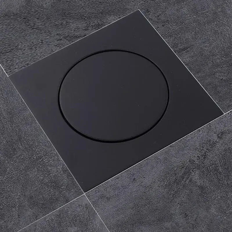Modern matte black brass shower floor drain with circular recessed center set in dark gray tiled flooring decorbites brass shower