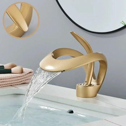 Gold-colored modern brass waterfall basin faucet with sleek sculptural design and smooth metallic finish for bathroom vanity