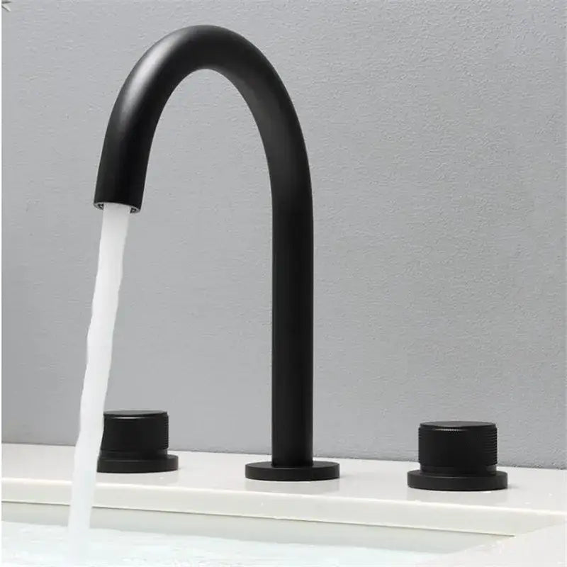 Modern matte black basin faucet with curved spout and cylindrical handles in brushed gold basin finish for bathroom sink