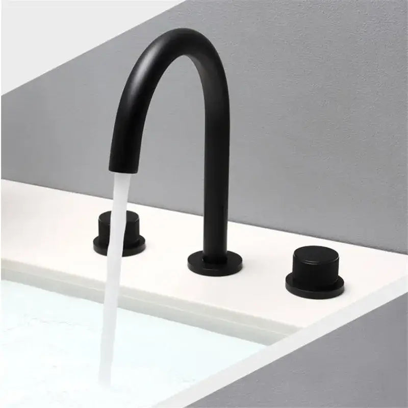 Modern matte black basin faucet with curved spout and two handles, complements brushed gold basin faucets in bathroom sinks