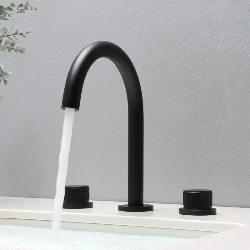 Modern matte black basin faucet with curved spout and two cylindrical handles for brushed gold basin bathroom sink