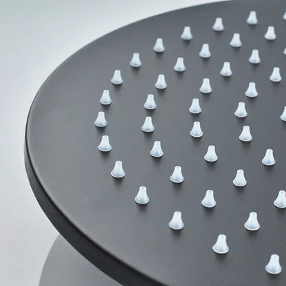 Black round brass rain shower head with evenly spaced white conical nozzles in a modern matte finish bathroom fixture