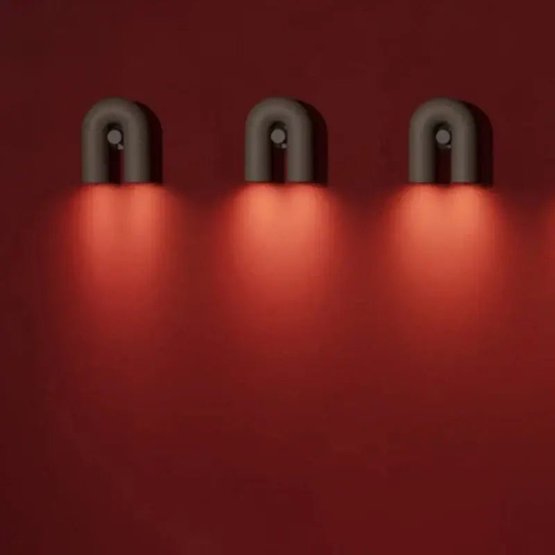 Three sleek matte black u-shaped tube wall lamps with warm red glow modern decorbites cirkus tube wall lamp