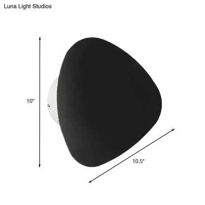 Modern matte black triangle wall lamp with a white mounting base designed for corridor lighting