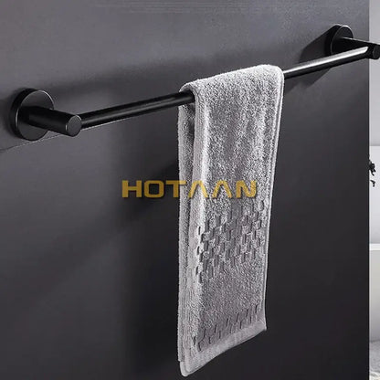 A soft gray towel hangs on a modern matte black wall mounted towel bar with wood accents for bathroom use