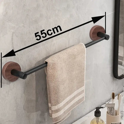 Modern matte black wall mounted towel bar with wood accents holding a beige textured towel on black wall mounted rack