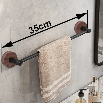 Modern matte black wall mounted towel bar with wooden circular ends holding a beige striped towel in bathroom