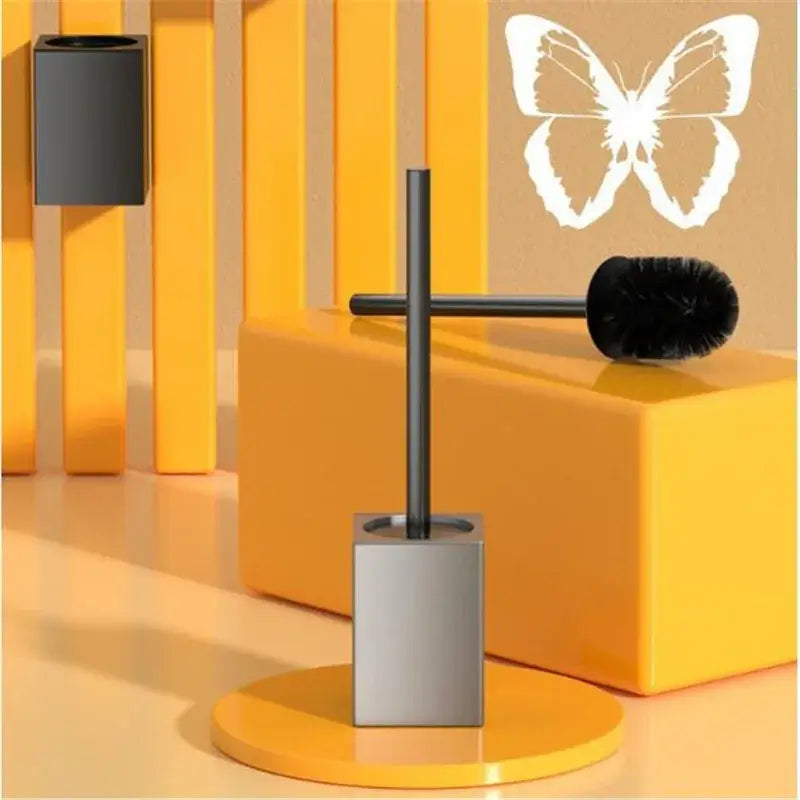Modern matte gray and black metal toilet brush holder set with sleek black brush and square base on yellow pedestal