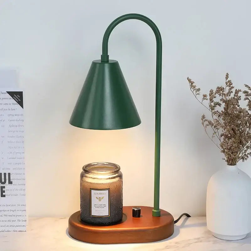 Modern matte green electric candle lamp with curved metal neck and wooden base holding amber glass candle warmer